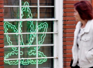 A pedestrian walks past a marijuana leaf neon sign advertising a medical marijuana provider along a street in the Sherman Oaks section of Los Angeles. (Photo by Richard Vogel)